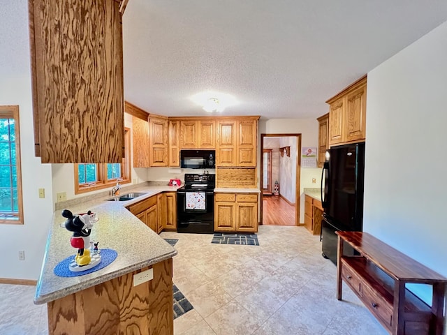 kitchen featuring kitchen peninsula, a textured ceiling, sink, and black appliances