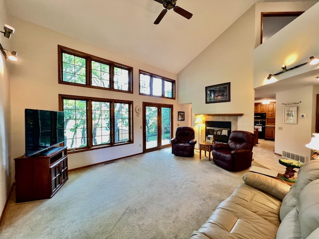 living room with ceiling fan, a fireplace, high vaulted ceiling, and light carpet