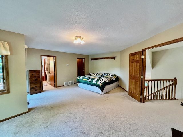 bedroom with a textured ceiling, connected bathroom, and carpet floors