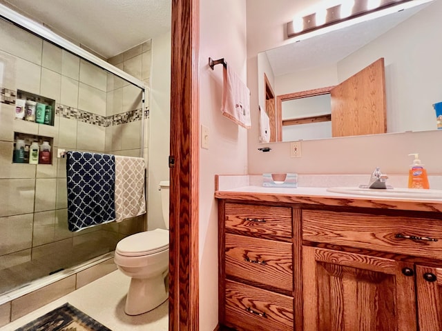 bathroom featuring a shower with door, vanity, and toilet