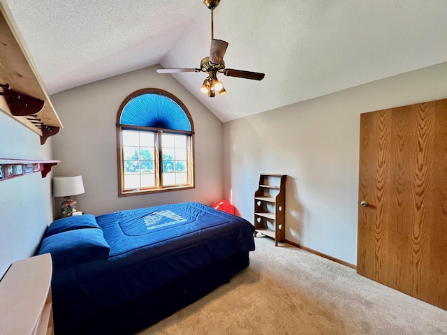 bedroom featuring a textured ceiling, ceiling fan, light colored carpet, and vaulted ceiling