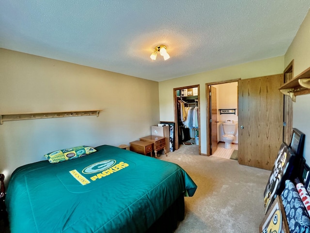 bedroom with carpet, ensuite bathroom, a textured ceiling, a spacious closet, and a closet