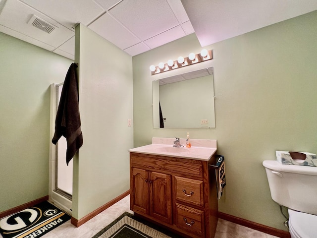 bathroom featuring a paneled ceiling, vanity, toilet, and a shower with door