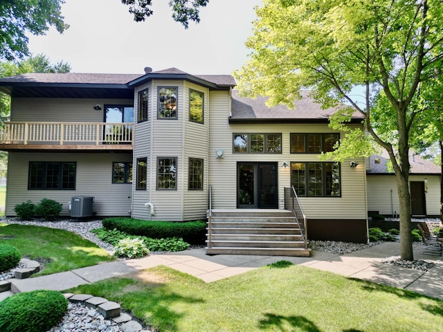 view of front facade featuring a front yard, a balcony, and central air condition unit