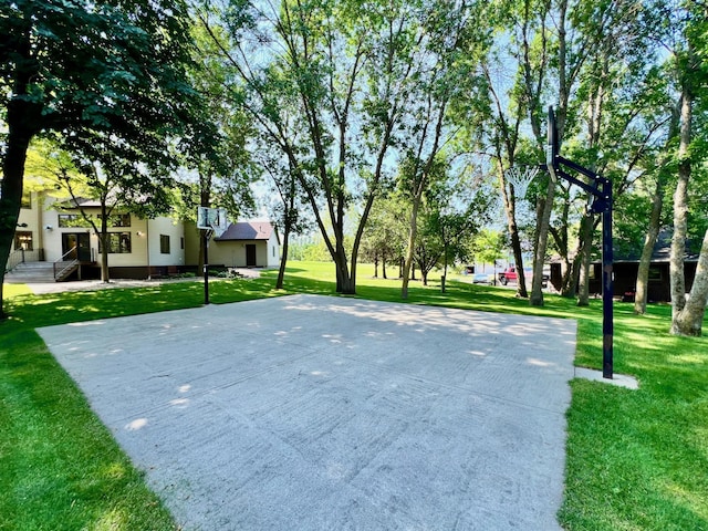 view of home's community featuring basketball hoop and a yard