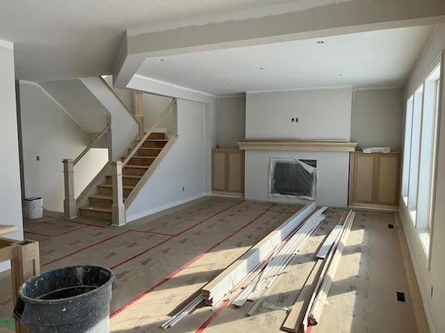 unfurnished living room with stairway and a fireplace