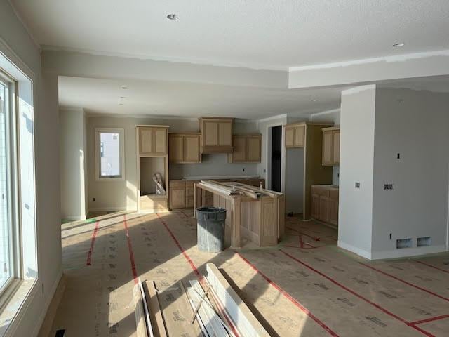 kitchen featuring a center island, baseboards, and light brown cabinetry