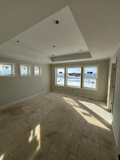 unfurnished room featuring a tray ceiling and baseboards