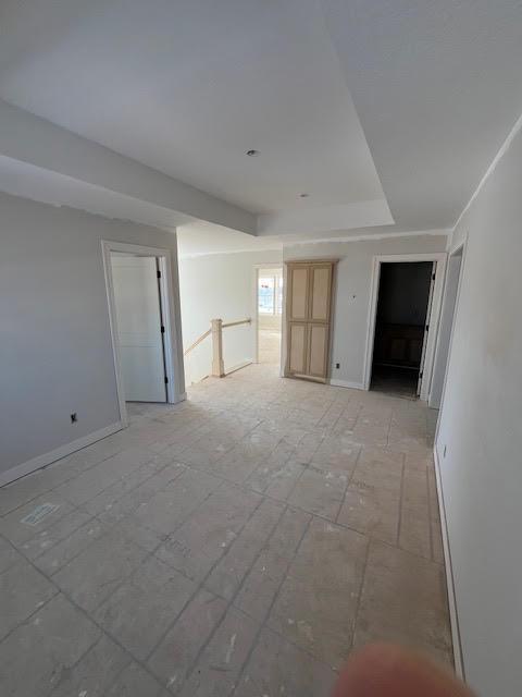 unfurnished room featuring a tray ceiling and baseboards