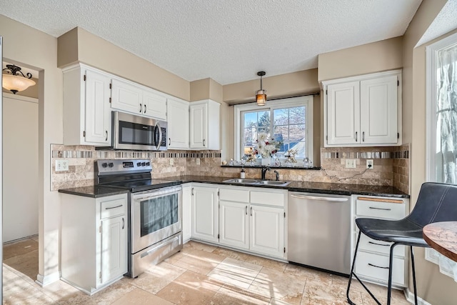 kitchen featuring appliances with stainless steel finishes, backsplash, sink, decorative light fixtures, and white cabinets