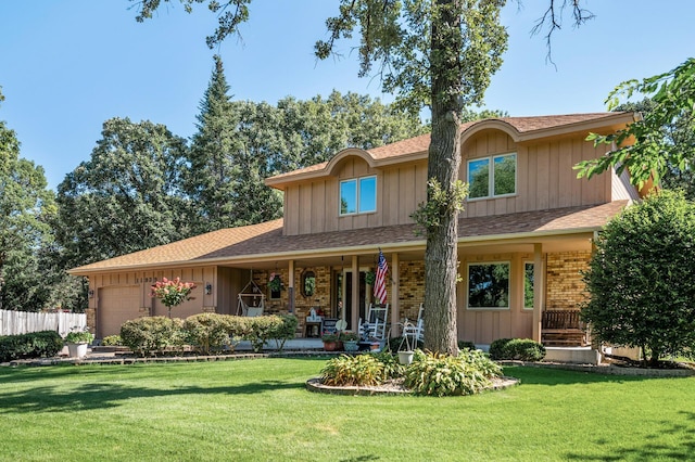 back of house with covered porch, a yard, and a garage