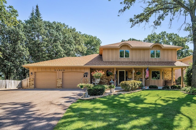 view of front of home with a porch, a front yard, and a garage