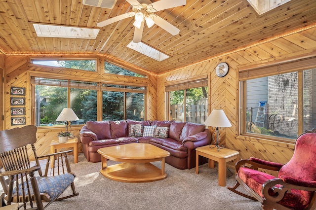 carpeted living room with vaulted ceiling with skylight, ceiling fan, wood ceiling, and a wealth of natural light