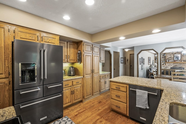 kitchen featuring appliances with stainless steel finishes, tasteful backsplash, light stone counters, a textured ceiling, and dark wood-type flooring