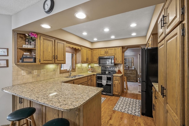 kitchen featuring range with two ovens, kitchen peninsula, sink, and black fridge