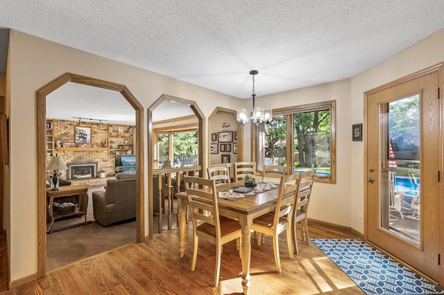 dining space with a fireplace, a textured ceiling, hardwood / wood-style flooring, and a wealth of natural light