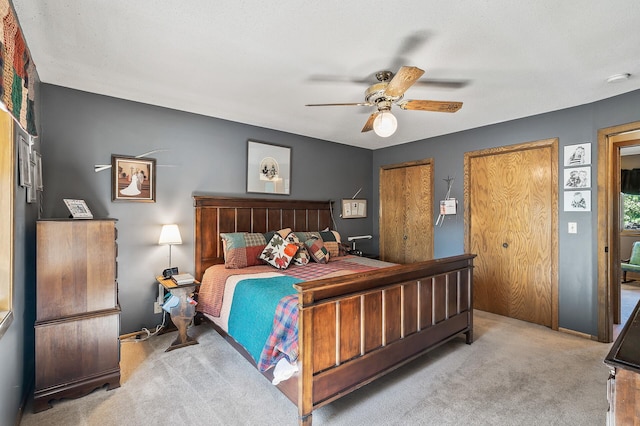 carpeted bedroom with two closets and ceiling fan