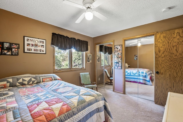 carpeted bedroom featuring a textured ceiling, ceiling fan, and two closets