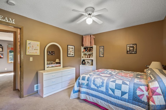 carpeted bedroom featuring ceiling fan and a textured ceiling