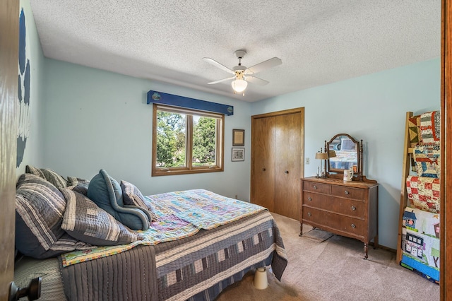 carpeted bedroom featuring ceiling fan, a closet, and a textured ceiling