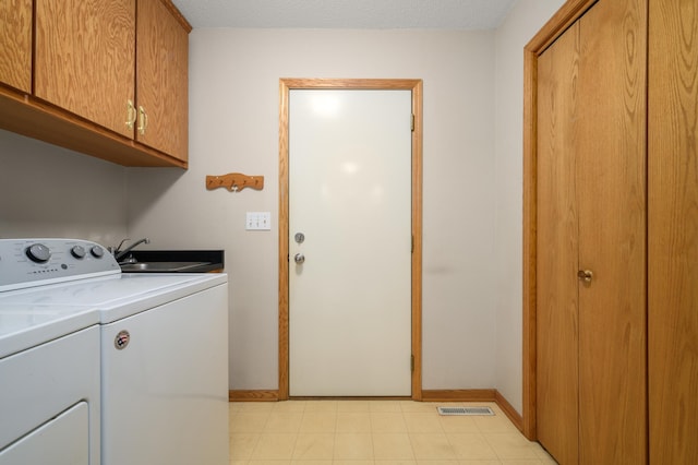 clothes washing area with separate washer and dryer, sink, and cabinets