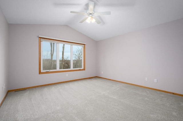 carpeted spare room featuring vaulted ceiling and ceiling fan