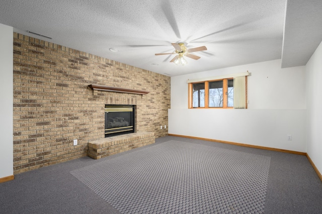 unfurnished living room with a brick fireplace, ceiling fan, a textured ceiling, carpet floors, and brick wall