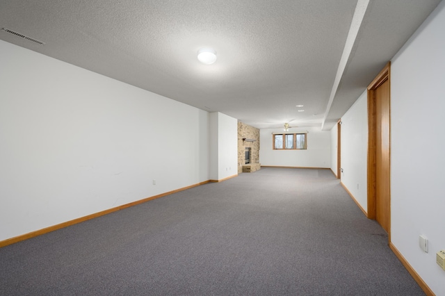 basement with carpet, a large fireplace, and a textured ceiling