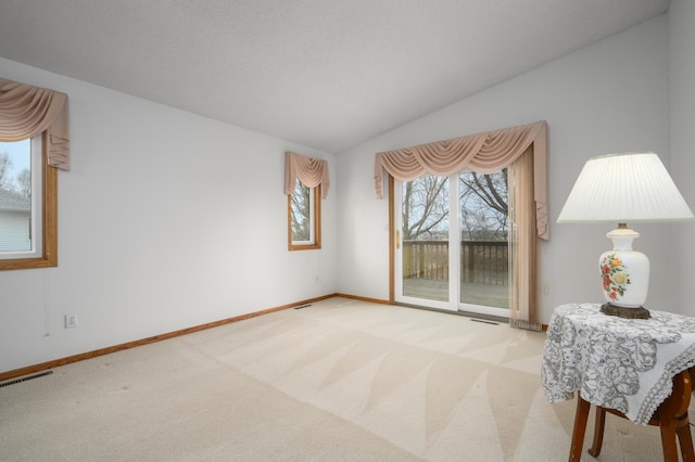 interior space featuring baseboards, vaulted ceiling, and visible vents