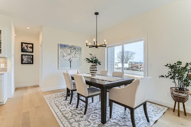 dining area with light wood-type flooring and an inviting chandelier