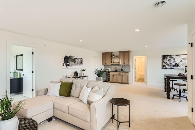 carpeted living room with beverage cooler and sink