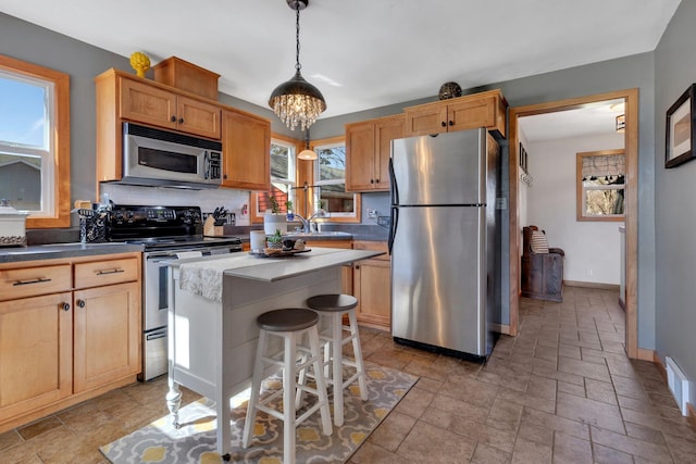 kitchen featuring a center island, tasteful backsplash, pendant lighting, a breakfast bar area, and appliances with stainless steel finishes