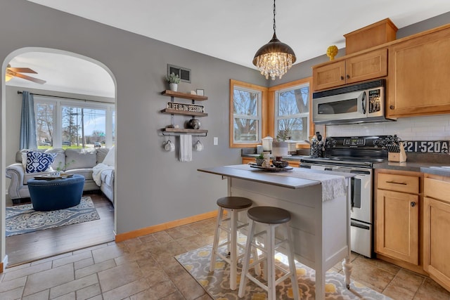 kitchen with a center island, tasteful backsplash, decorative light fixtures, a breakfast bar, and appliances with stainless steel finishes