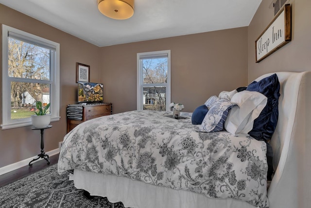 bedroom with dark hardwood / wood-style floors and multiple windows