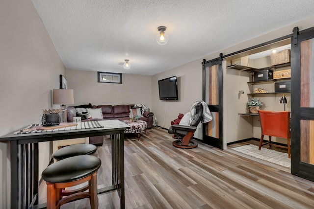 living room with a barn door, hardwood / wood-style floors, and a textured ceiling