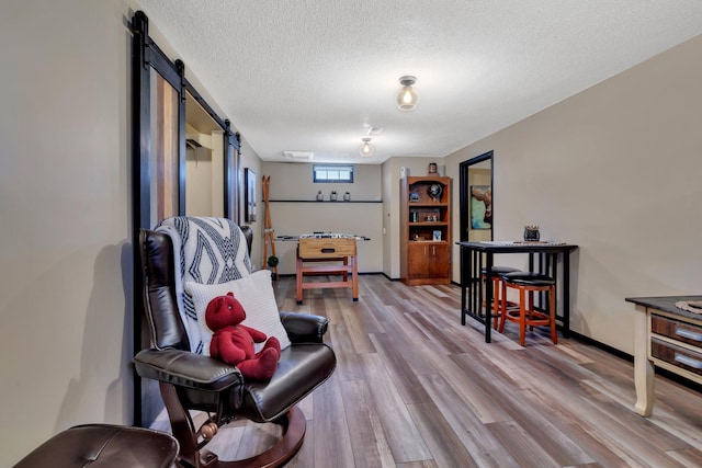 sitting room featuring hardwood / wood-style floors, a barn door, and a textured ceiling