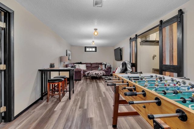 game room with wood-type flooring, a textured ceiling, and a barn door