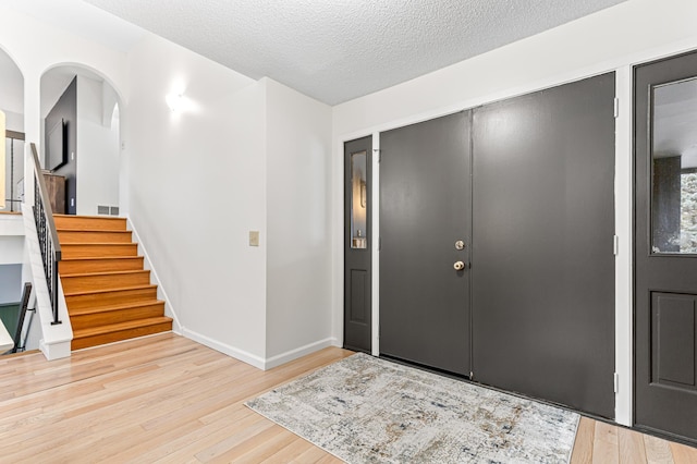 foyer entrance with light hardwood / wood-style floors and a textured ceiling