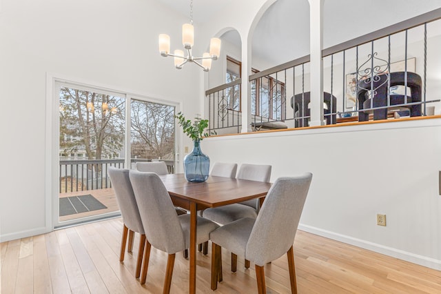 dining space featuring a high ceiling, a notable chandelier, and light wood-type flooring