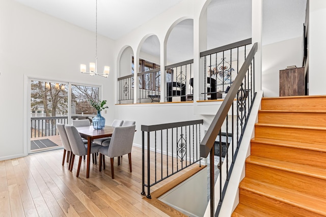 dining room featuring a towering ceiling, a chandelier, and light wood-type flooring