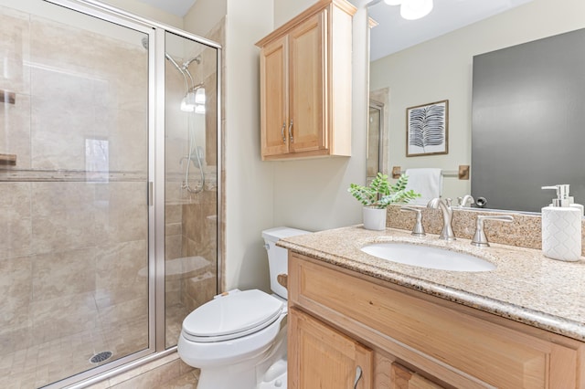 bathroom featuring vanity, toilet, and a shower with door