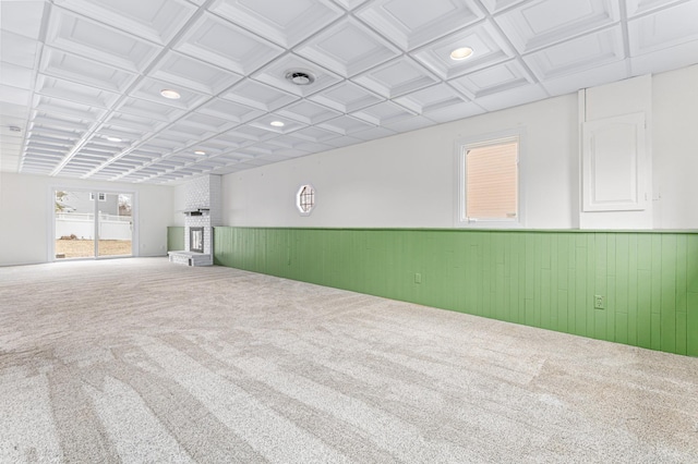 carpeted empty room with coffered ceiling and wooden walls