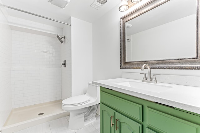 bathroom featuring vanity, tile patterned floors, toilet, and tiled shower