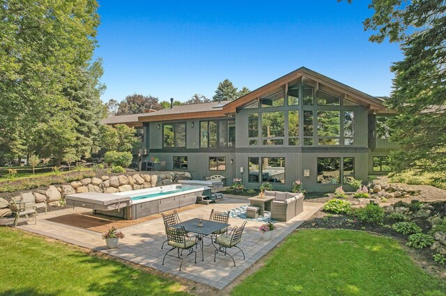 rear view of house with a patio area, a hot tub, and an outdoor hangout area