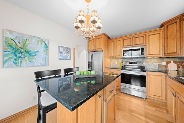 kitchen with appliances with stainless steel finishes, a center island, a breakfast bar, an inviting chandelier, and decorative light fixtures