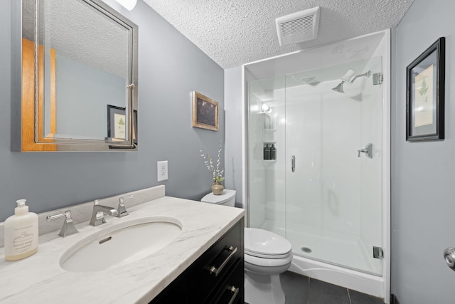 bathroom with a textured ceiling, toilet, tile patterned floors, a shower with door, and vanity