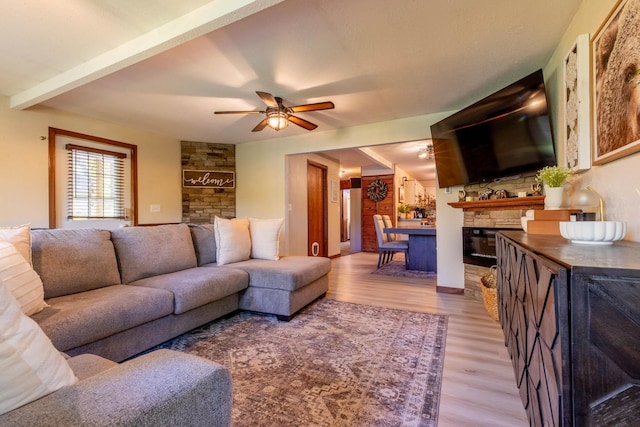 living room featuring a fireplace, ceiling fan, wood-type flooring, and beamed ceiling