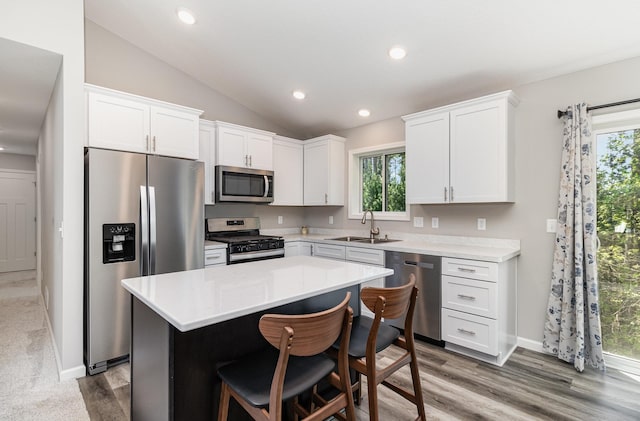 kitchen with a kitchen island, lofted ceiling, sink, white cabinets, and stainless steel appliances