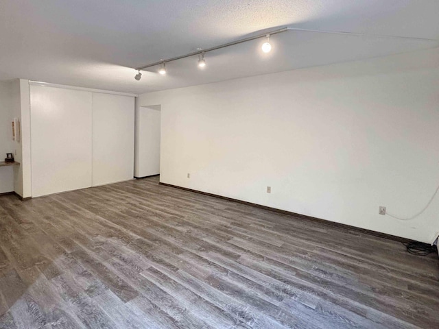 interior space with a textured ceiling, track lighting, and hardwood / wood-style flooring