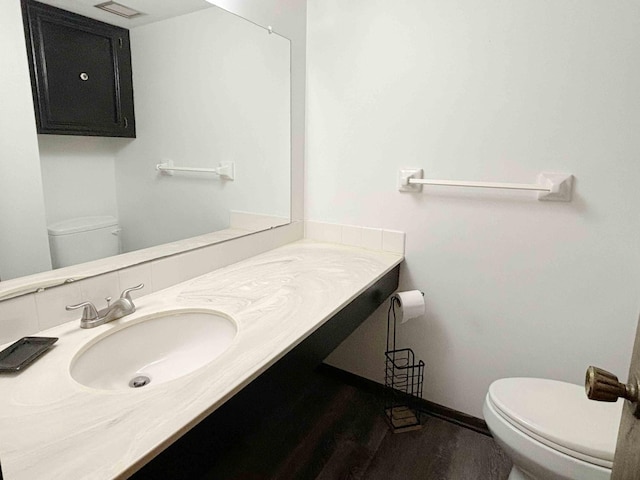 bathroom with wood-type flooring, vanity, and toilet